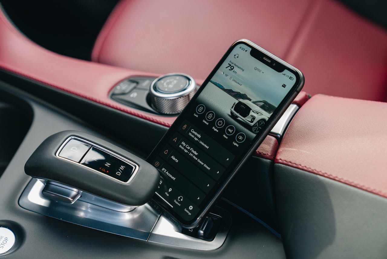 Close-up of smartphone with car control app in a luxury car's interior, showcasing modern technology.